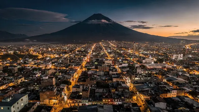 Vista aérea nocturna de una ciudad centroamericana al pie de un volcán
